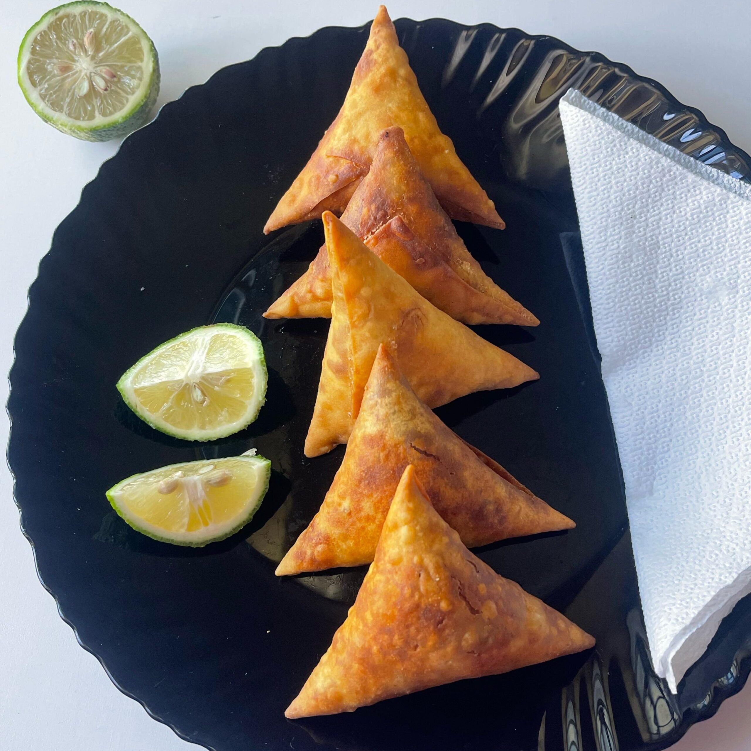 Fresh crispy samosas served with some lemon slices.