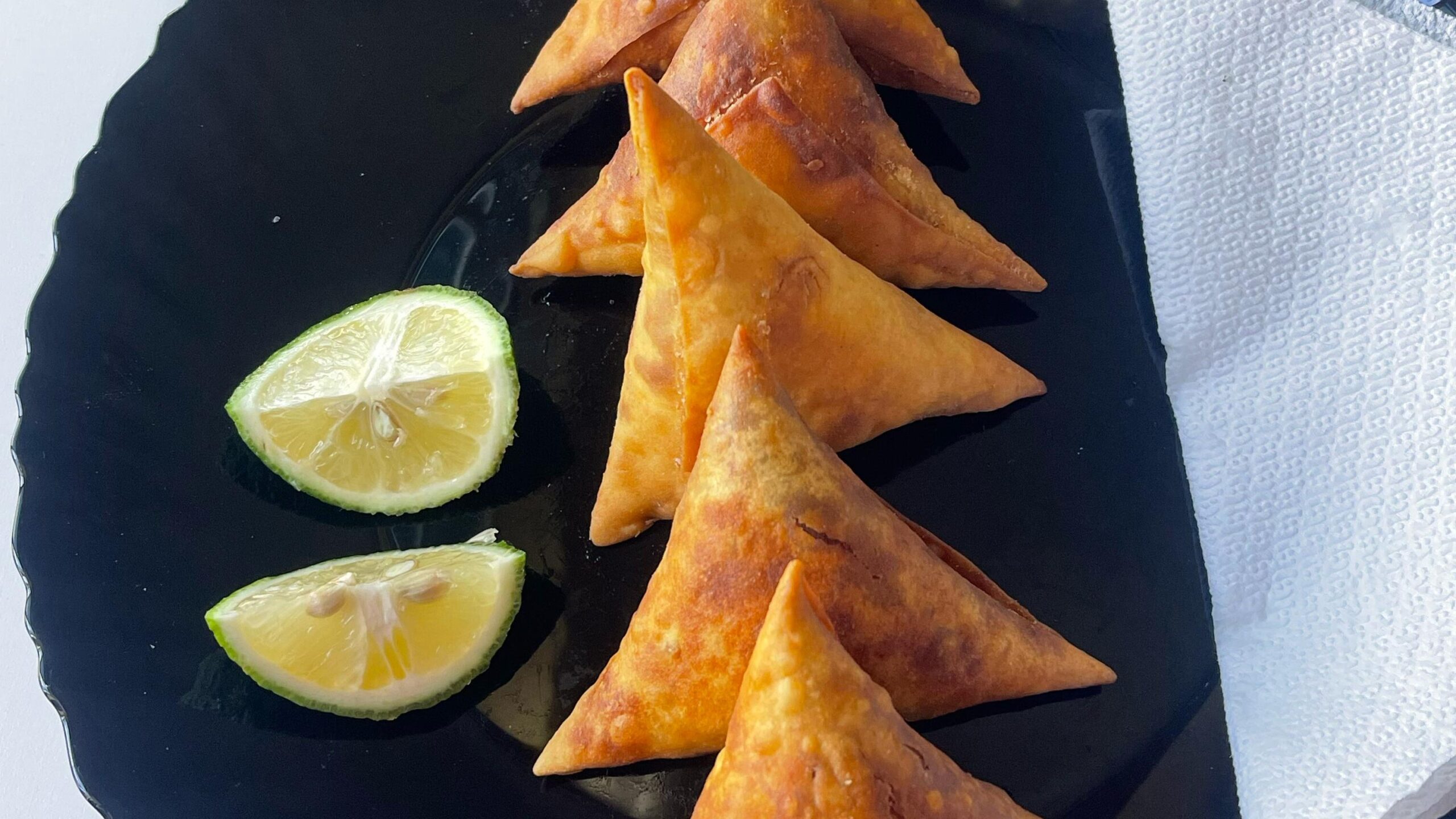 Fried samosas served with lime
